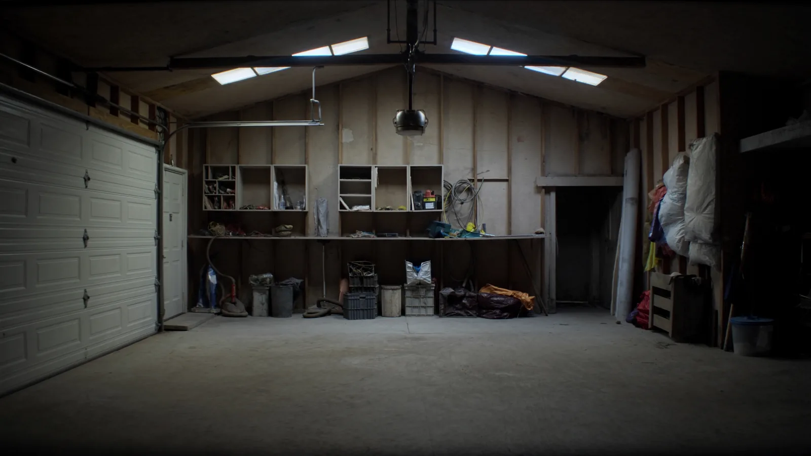 Unfinished Tacoma attached garage before conversion — bare concrete slab, exposed studs, garage door